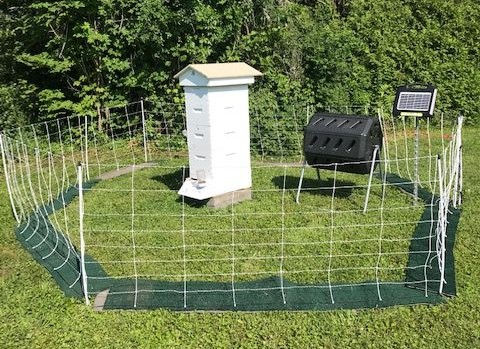 Composting tumbler behind electric fence